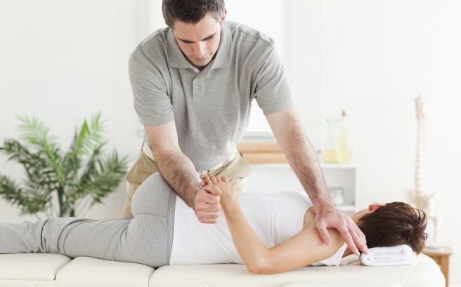 Masseur stretching woman's arm