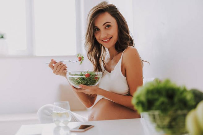 femeie-gravidă-care-zâmbește-și-mănâncă-dintr-o-salată-ca-super-alimente