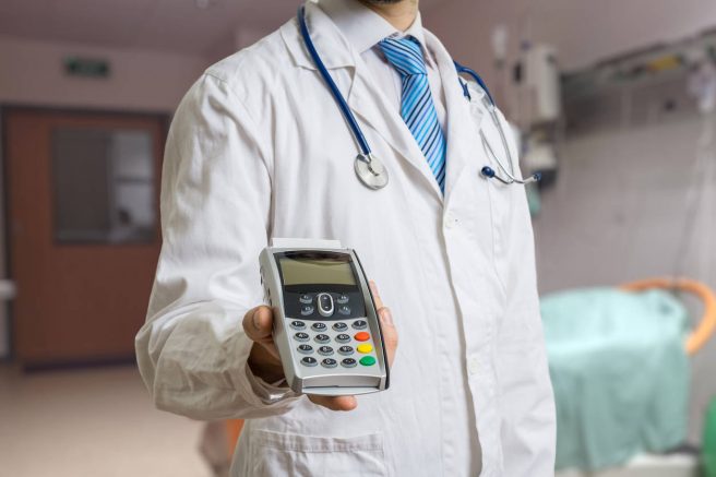 Medic care tine in mana o casa de marcat mobila si are de gat atarnat un stetoscop