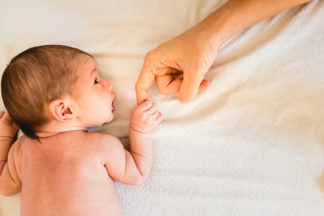 bebelus-care-se-tine-cu-manuta-de degetul-mame-lui-aflata-in-perioada-de-lauzie
