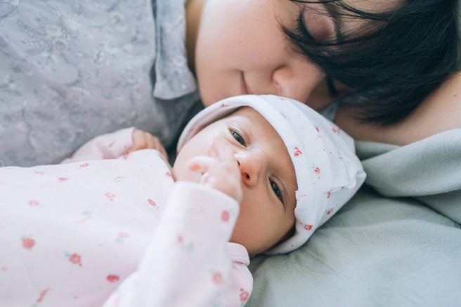 bebelus cu ochii deschisi langa mama