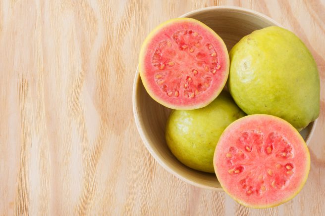 fructe-de-guava-intregi-intr-un-bol-si-un-alt-fruct-de-guava-taiat-ce-are-miezul-rosu-de-pe-lista-cu-fructe-recomandate-in-sarcina