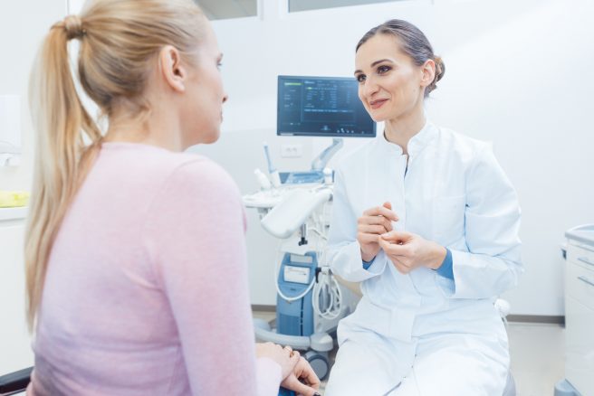 femeie la control ginecologic discuta cu medicul in fata aparaturii medicale
