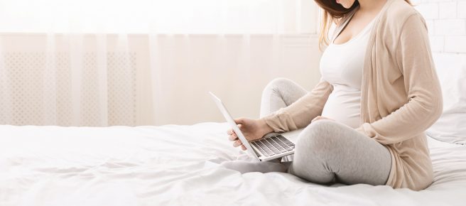 femeie-gravida-sta-in-pat-cu-un-laptop-si-cauta-pe-froum-despre-superstitii-in-sarcina