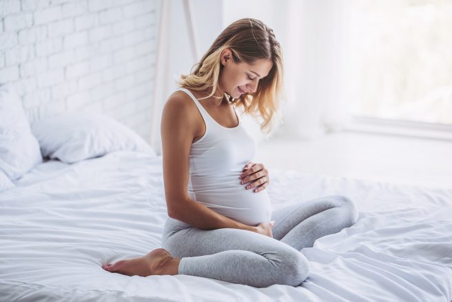 tratament-pentru-colestaza-de-sarcina-iar-o-femeie-blonda-gravida-sta-in-pat-se-uita-spre-burtica-si-o-mangaie