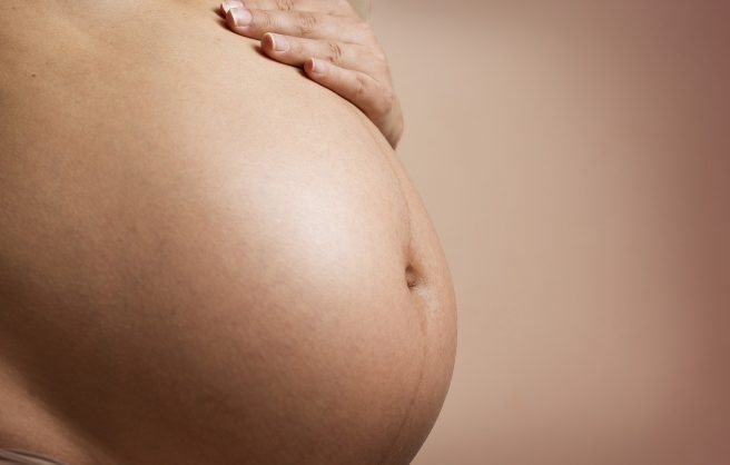Burtă de femeie însărcinată și mâna acesteia