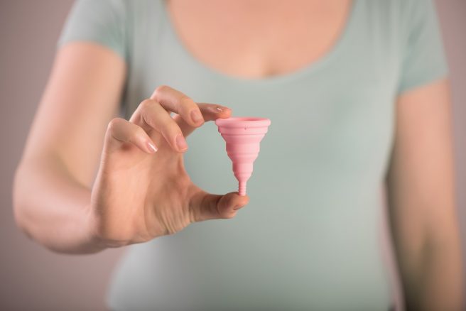 Femeie care ține în mână o cupă menstruală