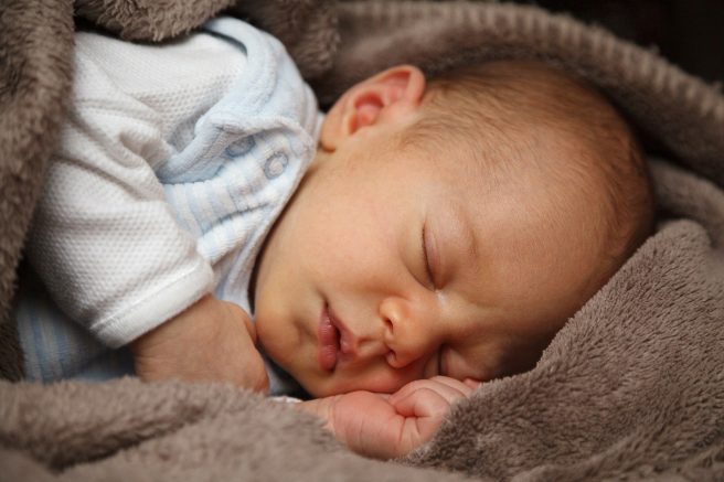 Bebeluș care doarme înconjurat de pătură