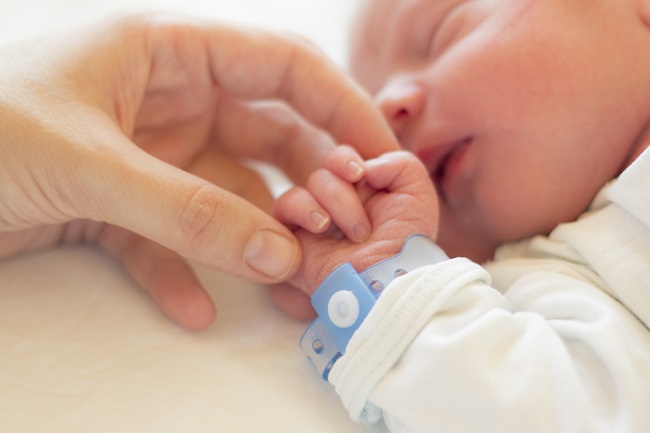 baietel-nou-nascut-care-doarme-cu-bratara-albastra-la-mana-si-mama-lui-care-il-tine-de-mana-dupa-vaccin-anticovid-in-sarcina