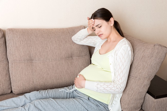 gravidă-care-are-durere-de-cap-și-este-balonată-și-care-stă-întinsă-pe-o-canapea