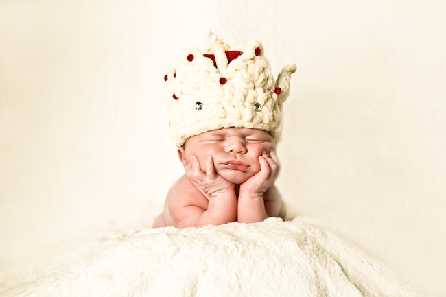 bebeluș-care-stă-cu-mâinile-la-bărbie-și-cu-ochii-închiși-și-are-o-coroană-pe-cap-pentru-tradiții-la-nașere