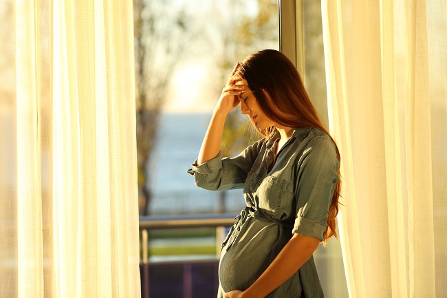 femeie-gravida-cu-dureri-de-cap-in-sarcina-care-sta-langa-fereastra