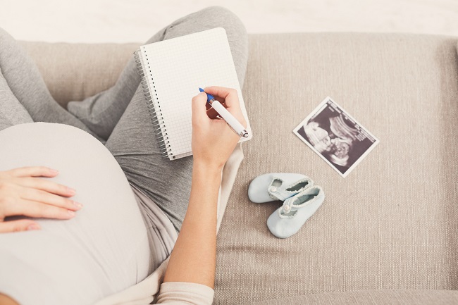 femeie-gravidă-care-scrie-într-un-carnet-și-are-lângă-ea-o-ecografie-și-pantofi-pentru-bebeluș