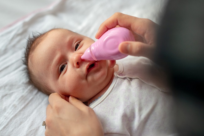 femeie-care-curata-nasul-bebelusului-cu-o-pompa-nazala-roz-dupa-nas-înfundat-copii