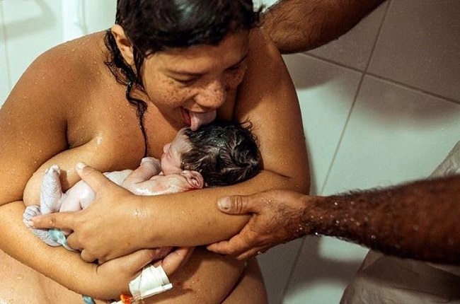 mamă-care-își-linge-bebelușul-pe-cap-pentru-a-respecta-obiceiuri-la-naștere