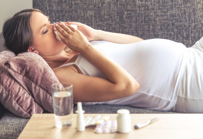 Femeie însărcinată care suflă nasul