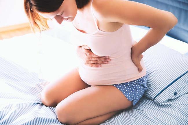 femeie-gravida-care-sta-ghemuita-in-pat-si-are-dureri-de-spate-si-burta-ca-simptom-pentru-dezlipire-de-placentă